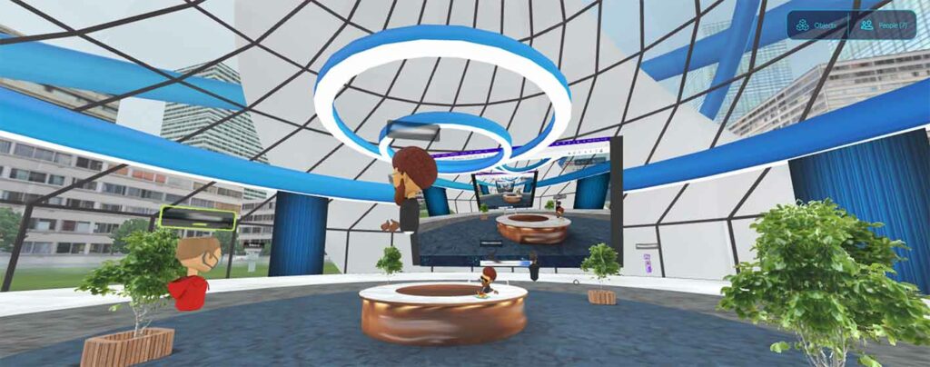 Screenshot of a metaverse meeting at work. There is a dome-like circular room with a virtual reception area, a few floating avatars, and a digital screenshare in one section