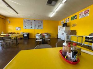 Bright yellow walls with a few tables at Hot Dogs La Reyna in Tucson