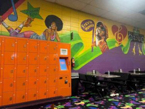 Orange lockers and tables with a mural in the background at Skate Country in Tucson